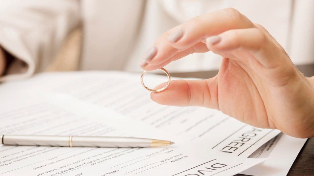 Woman holding a wedding ring over divorce papers